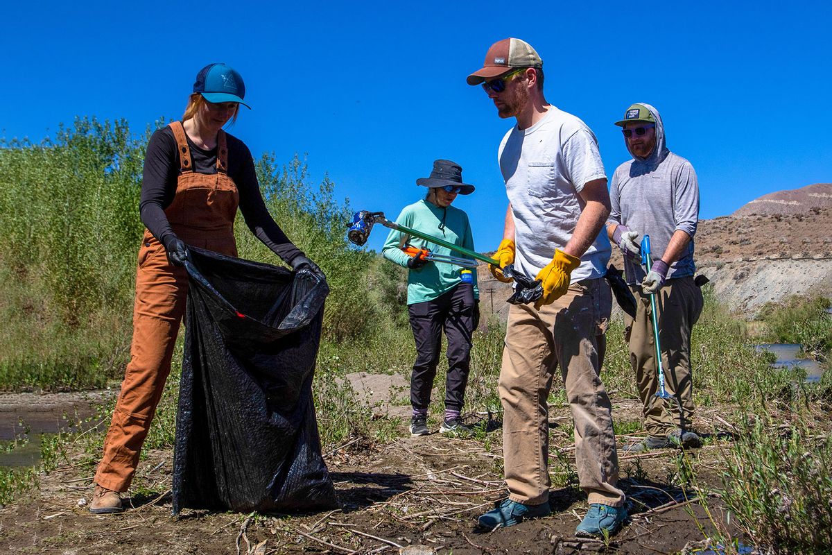 A group of volunteers removing trash from the side of the Truckee river in Mustang Ranch Trail. (Ty ONeil/SOPA Images/LightRocket via Getty Images)