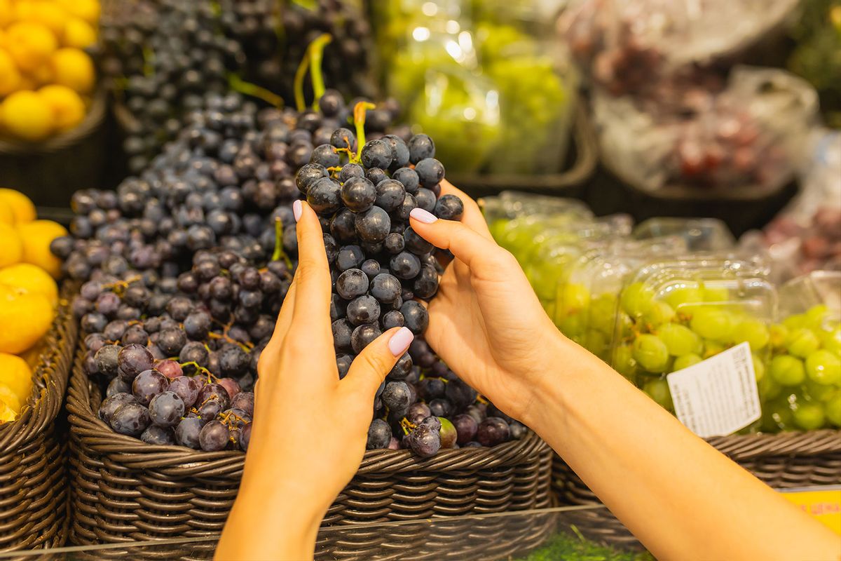 Woman choosing grapes at grocery store (Getty Images/iiievgeniy)