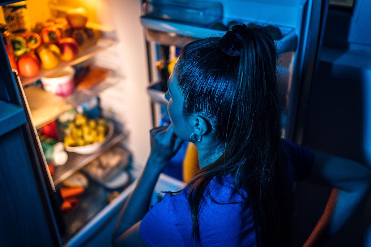 Young woman in front of the refrigerator at night (Getty Images/LordHenriVoton)