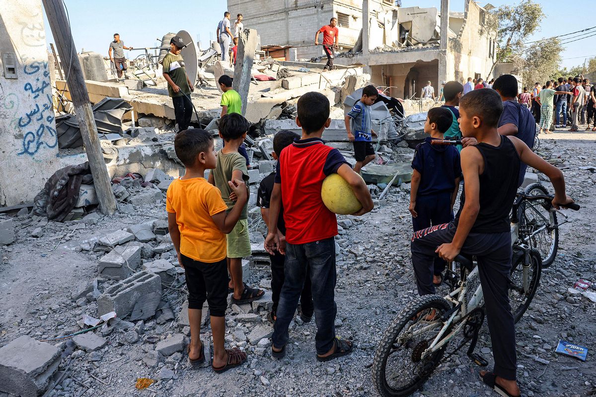 Children watch as civil defense responders search for victims in the rubble of a building after an Israeli air strike in Rafah in the southern Gaza Strip on October 13, 2023. (SAID KHATIB/AFP via Getty Images)