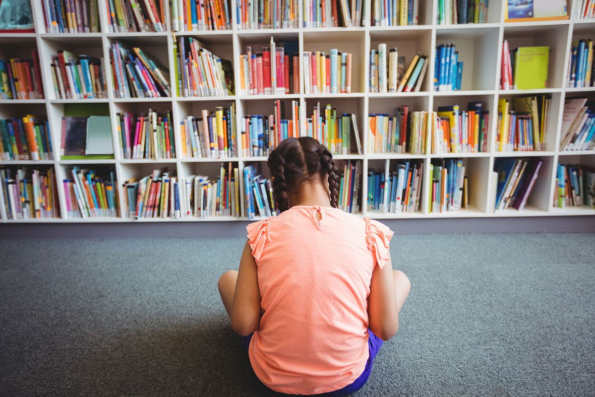 Rear view of girl reading a book in the library (Getty Images/Wavebreakmedia)