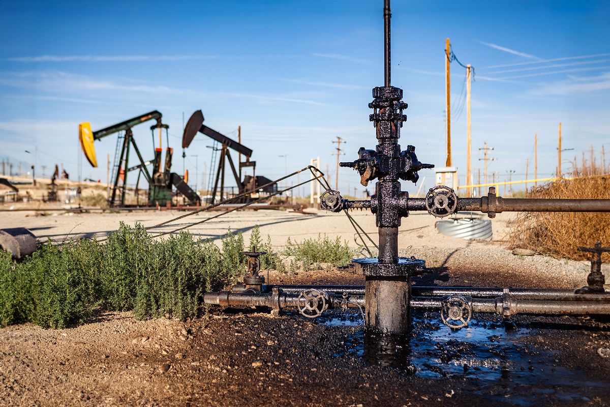 An oil pumpjack with a leaky wellhead is dripping with oil into a puddle along the side of a road through the Midway-Sunset oil field in Kern County, California. (Getty Images/Gary Kavanagh)