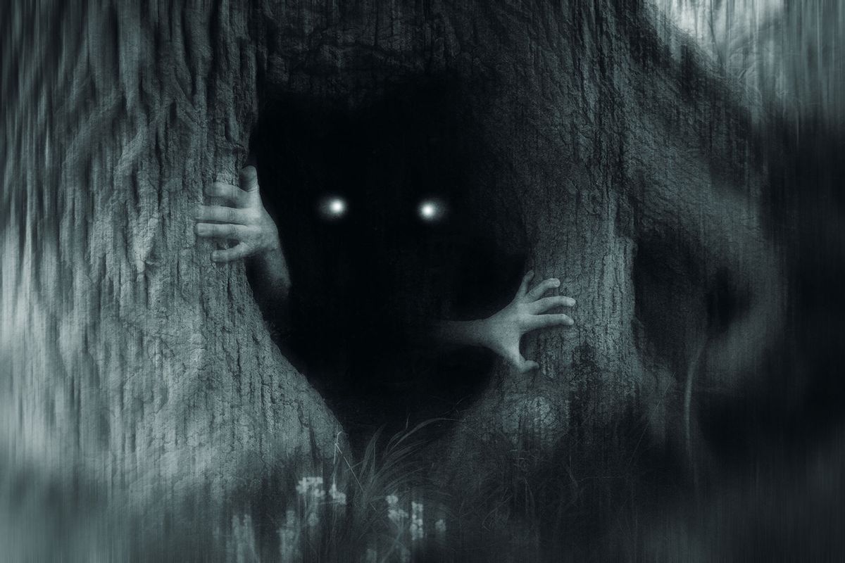 A spooky horror concept of a monster with glowing eyes, hiding in a tree trunk, in a dark spooky forest. (Getty Images/David Wall)
