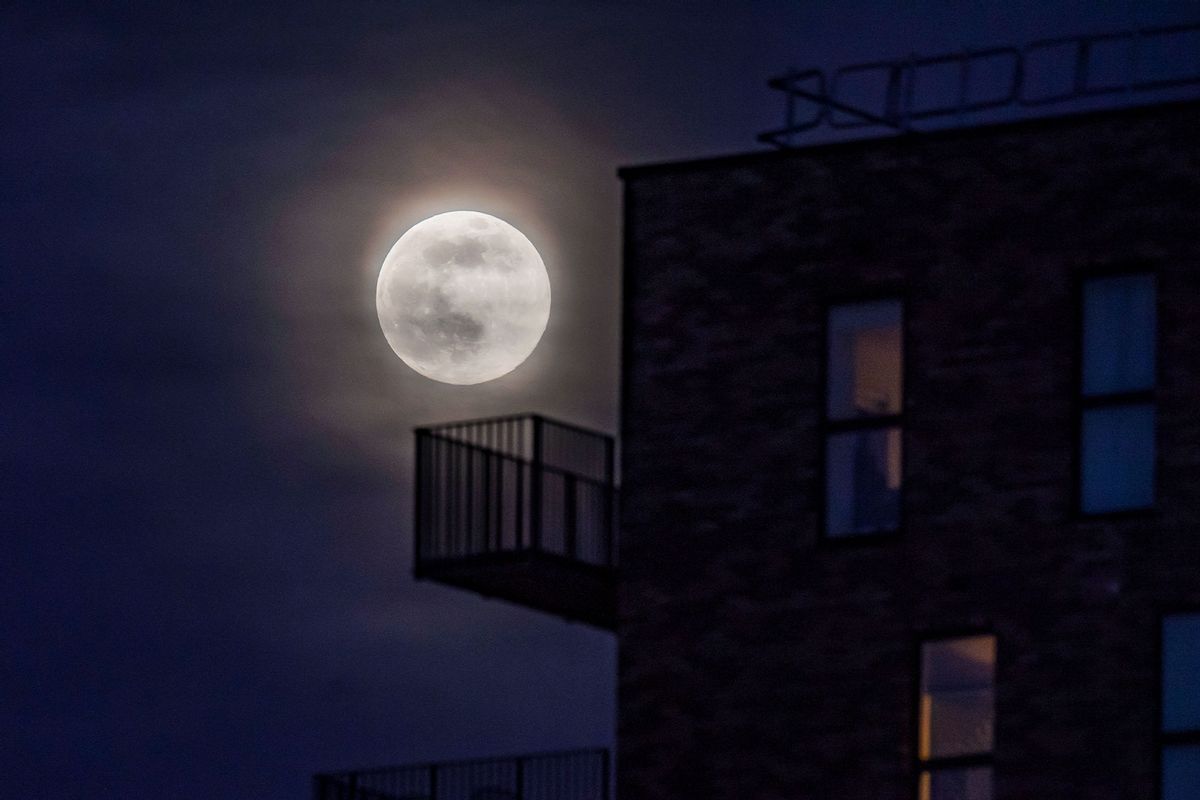 The supermoon rises behind clouds above an apartment block on April 07, 2020 in Manchester, United Kingdom. (Anthony Devlin/Getty Images)