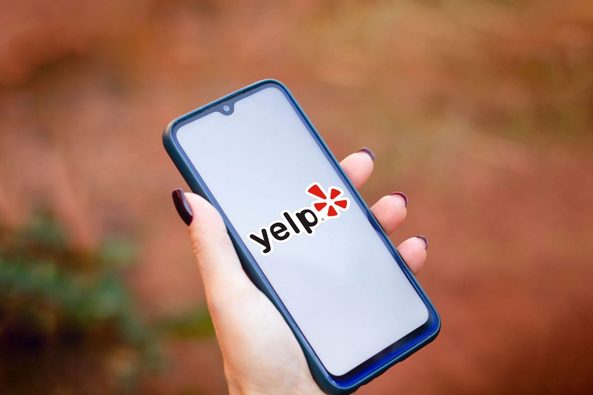 In this photo illustration a hand holding a smartphone displaying the Yelp logo on a screen. (Photo Illustration by Rafael Henrique/SOPA Images/LightRocket via Getty Images)