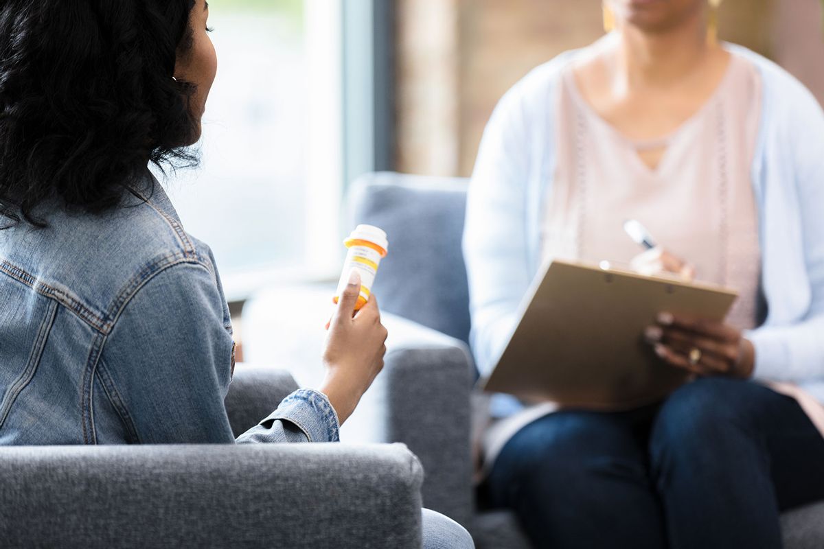 The young woman holds onto the prescription bottle while she listens to the doctor (Getty Images/SDI Productions)