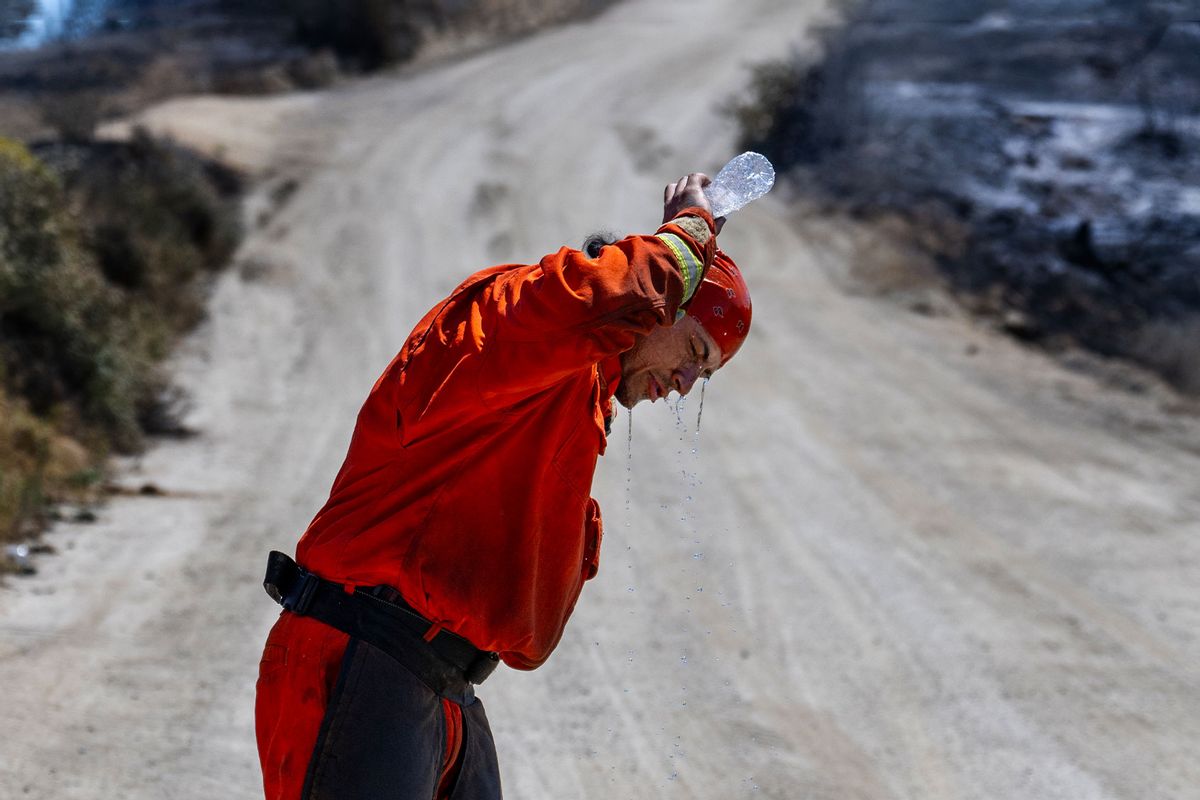 A member of the Prado fire crew pours water over his head to cool off in the 105 degree heat while putting out hotspots at the Rabbit fire on July 16, 2023 in Beaumont, CA. (Gina Ferazzi / Los Angeles Times via Getty Images)