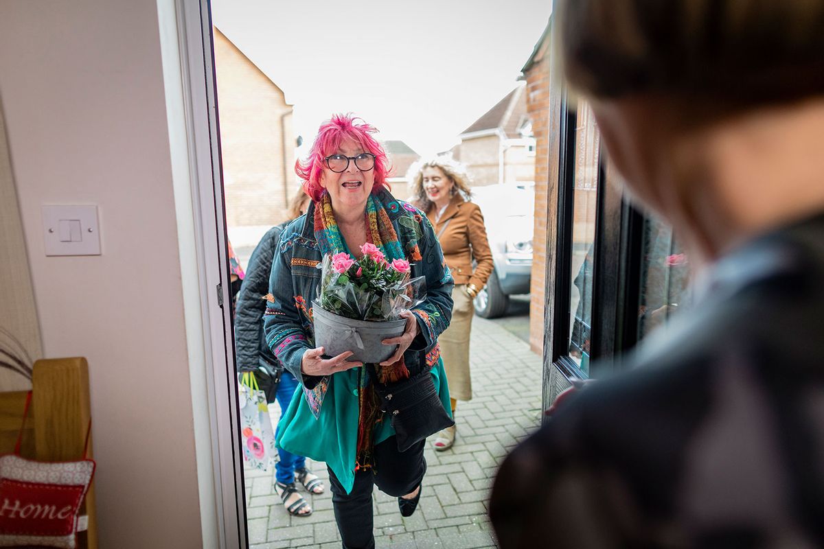 Woman is arriving at her friends house for a dinner party with flowers in her arms. (Getty Images/SolStock)
