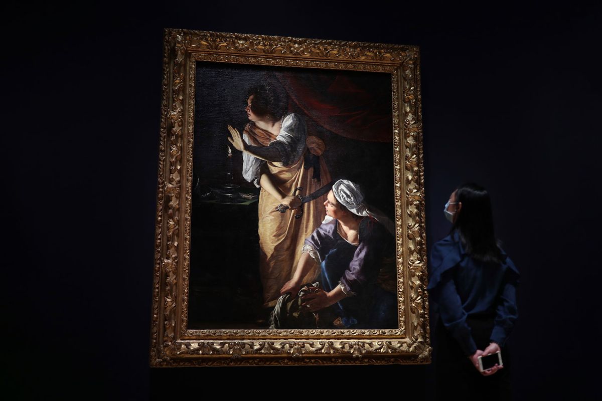 National Gallery staff member Jean Tang poses next to the work Judith and her Maidservant with the Head of Holofernes, about 1623-5, during a photo call to preview the National Gallery's forthcoming Artemisia exhibition in London. (Yui Mok/PA Images via Getty Images)