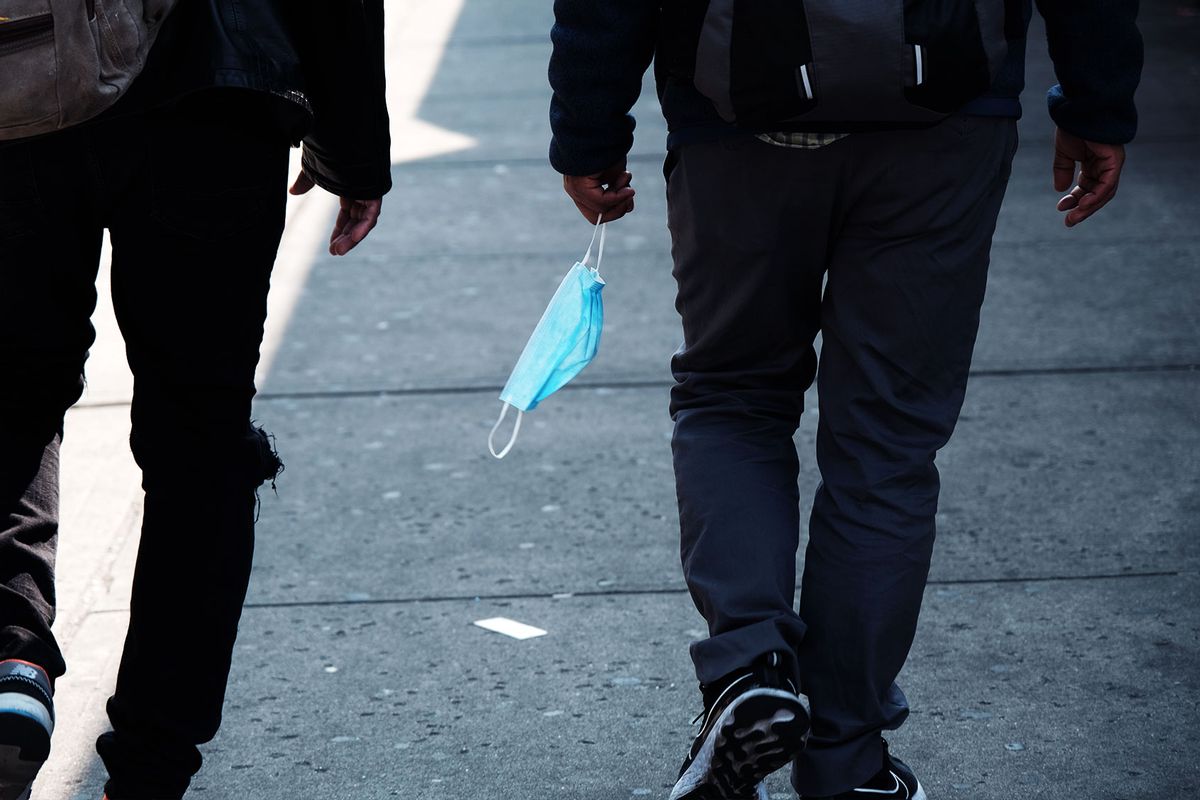 A man carries a mask as he walks along Roosevelt Avenue, which passes through the neighborhoods of Elmhurst, Corona and Jackson Heights, areas that witnessed some of the highest numbers of Covid-19 cases and deaths on May 11, 2023 in the Queens borough of New York City. (Spencer Platt/Getty Images)