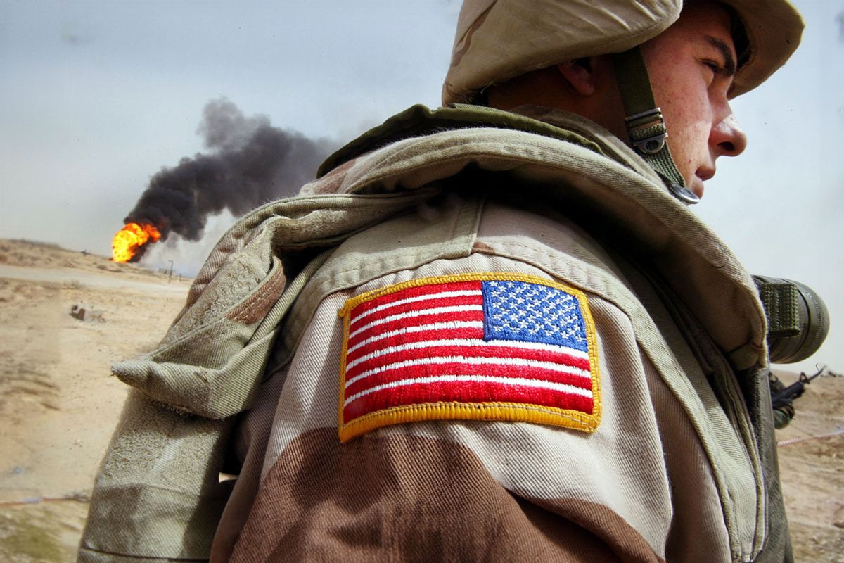U.S. Army Specialist stands next to a burning oil well at the Rumayla oil fields March 27, 2003 in Rumayla, Iraq. (Mario Tama/Getty Images)