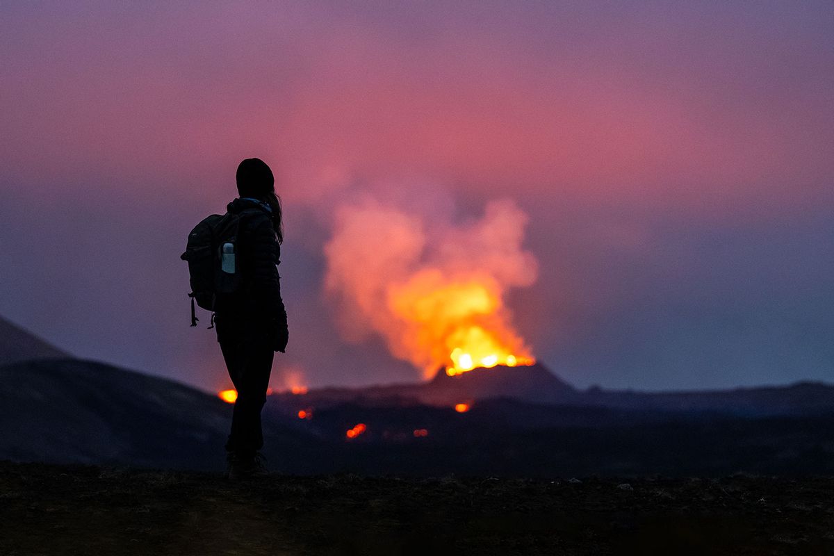 21 July 2023, Iceland, Fagradalsfjall: Lava erupts from the crater of a volcano near the mountain Litli-Hrútur, about 40 kilometers southwest of Reykjavik. A young woman stands in the foreground, gazing at the flames. (Philipp Schulze/picture alliance via Getty Images)
