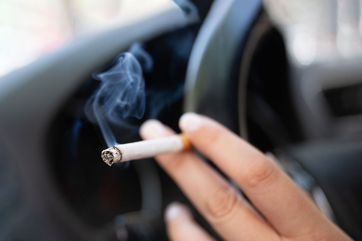 A woman sits in a car and holds a cigarette. (Sebastian Kahnert/picture alliance via Getty Images)