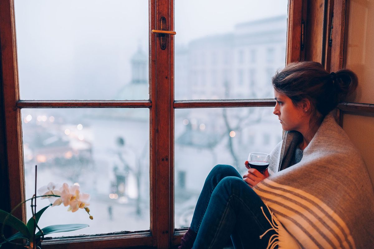 Depressed woman sitting near the window (Getty Images/Martin Dimitrov)