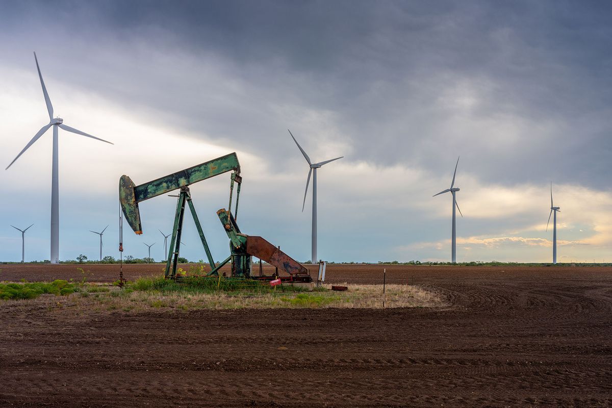 An oil pumpjack is seen near a field of wind turbines on October 04, 2023 in Nolan, Texas. (Brandon Bell/Getty Images)