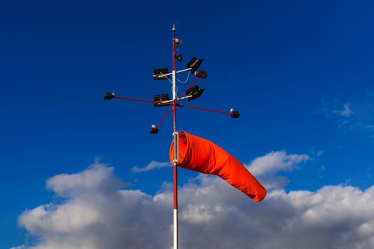 Bright orange windsock tied to a light signal post while catching a breeze (Getty Images/Sunphol Sorakul)