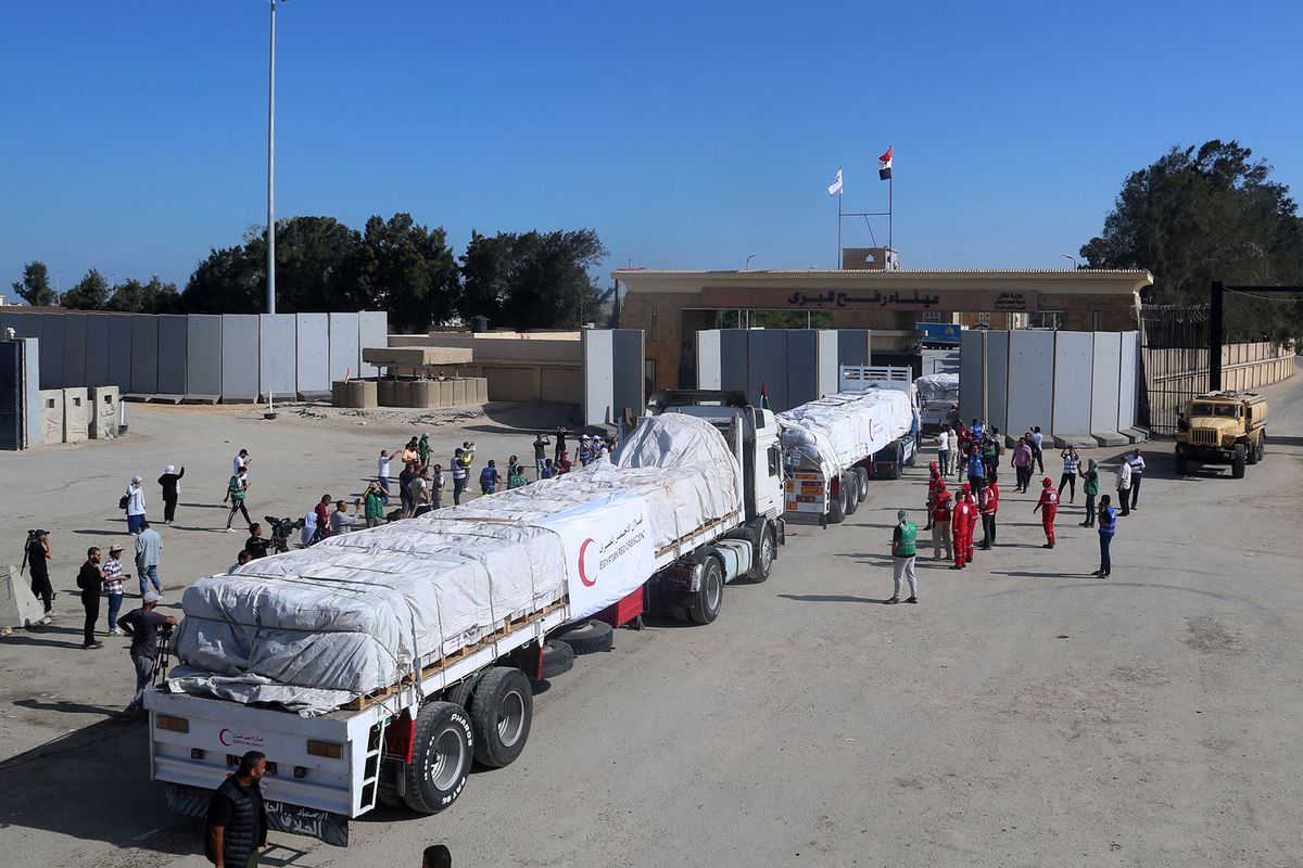 People on the Egyptian side of the Rafah border crossing watch as a convoy of lorries carrying humanitarian aid crosses to the Gaza Strip on October 21, 2023. (MOHAMMED ASSAD/AFP via Getty Images)