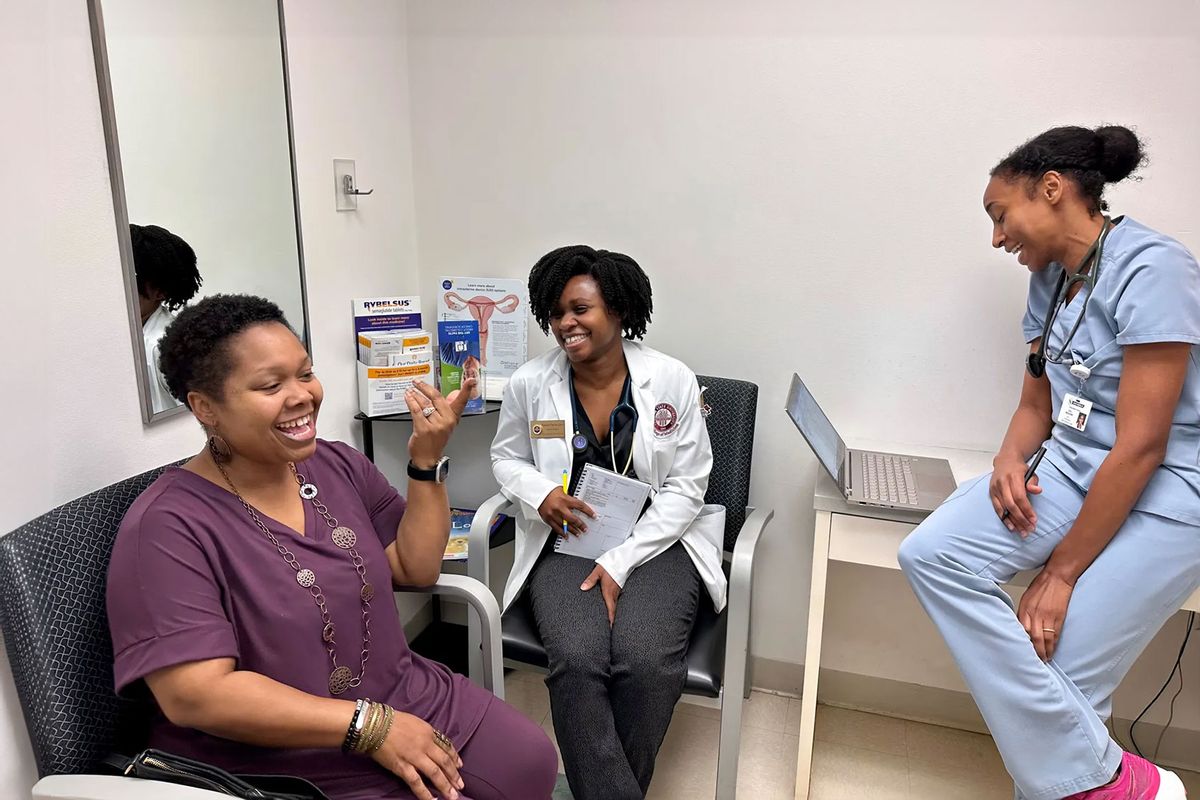 YaSheka Shaw (left) celebrates losing weight during a checkup with medical student Kaniya Pierre Louis (center) and physician Zita Magloire. (Sarah Jane Tribble/KFF News)