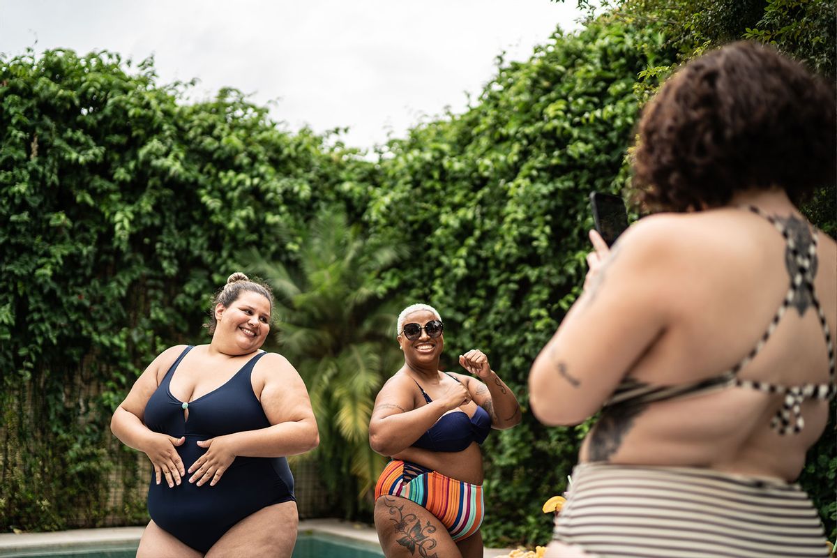 Female friends dancing for social media and filming it on mobile phone in the pool at home (Getty Images/FG Trade)