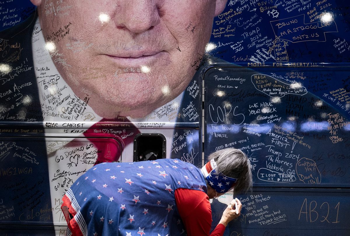 A person signs a bus wrapped with an image of former President Donald Trump during the Conservative Political Action Conference (CPAC) in National Harbor, Maryland, on February 22, 2024.  (BRENDAN SMIALOWSKI/AFP via Getty Images)