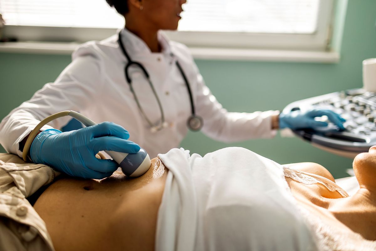 Doctor performs ultrasound examination of a woman (Getty Images/ljubaphoto)