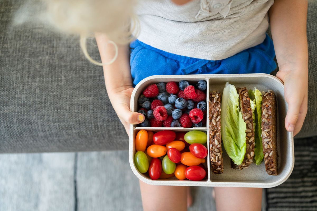 Hands of girl holding lunch box with healthy food on sofa at home (Getty Images/Westend61)