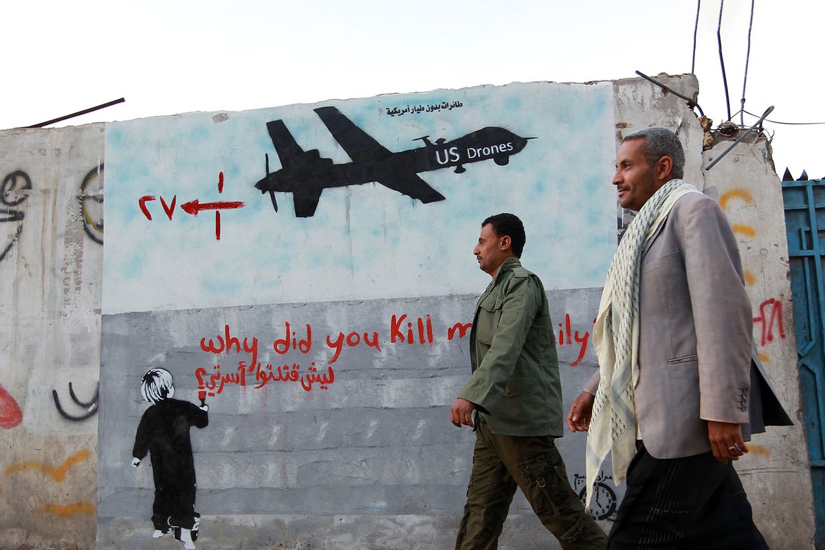 Yemeni men walk past a mural depicting a US drone and reading " Why did you kill my family" on December 13, 2013 in the capital Sanaa. (MOHAMMED HUWAIS/AFP via Getty Images)