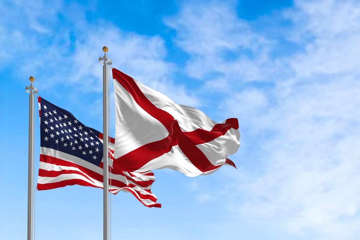 The flag of the state of Alabama waving alongside the national flag of the United States on a sunny day (Getty Images/rarrarorro)