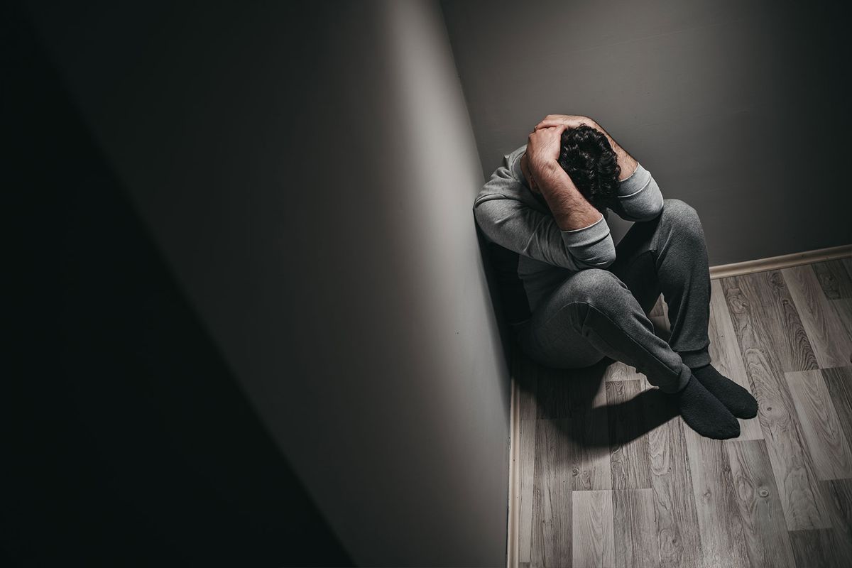 Man stressed, depressed in the corner of a room (Getty Images/urbazon)