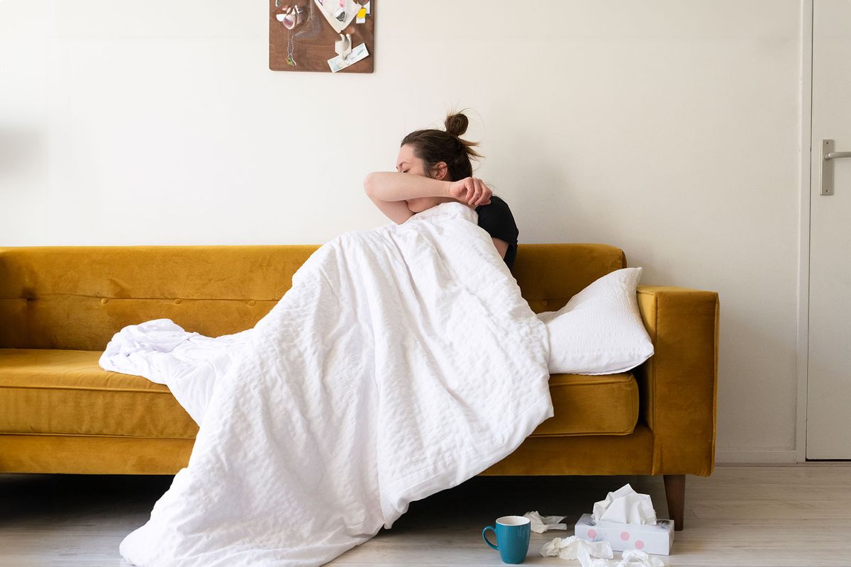 A woman feeling sick in her living room. (Getty Images/Roos Koole)