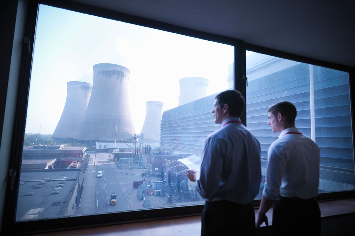 Workers looking over at nuclear power plant cooling towers (Getty Images/Monty Rakusen)