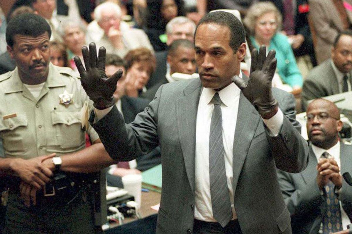 O.J. Simpson shows the jury a new pair of Aris extra-large gloves, similar to the gloves found at the Bundy and Rockingham crime scene 21 June 1995, during his double murder trial in Los Angeles,CA. Deputy Sheriff Roland Jex(L) and Prosecutor Christopher Darden (R) look on. (VINCE BUCCI/AFP via Getty Images)