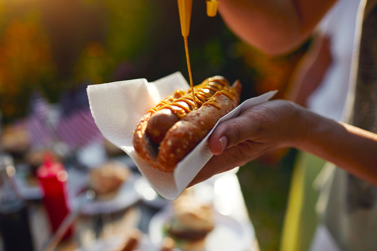 Putting mustard on a hotdog (Getty Images/vgajic)