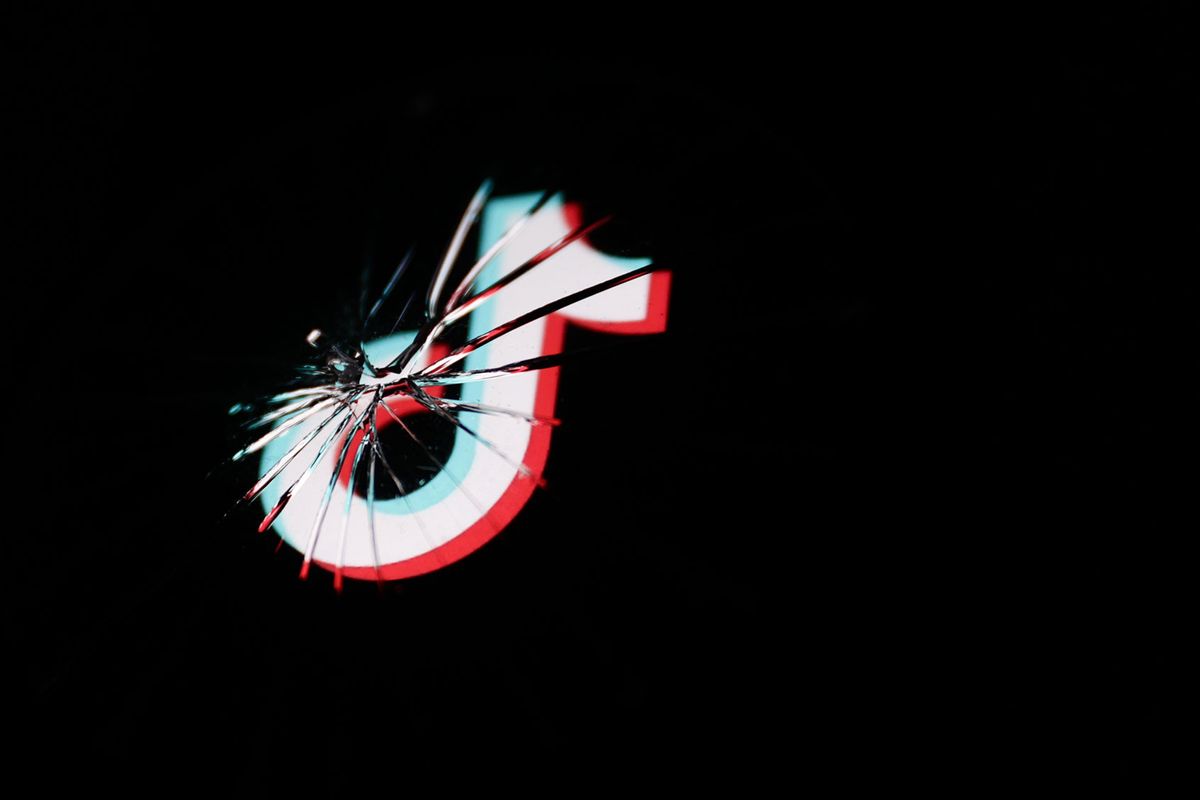 TikTok logo displayed on a phone screen is seen through broken glass. (Jakub Porzycki/NurPhoto via Getty Images)