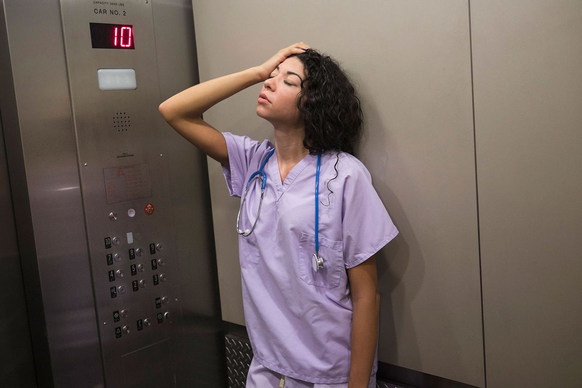 Stressed nurse standing in elevator (Getty Images/JGI/Tom Grill)