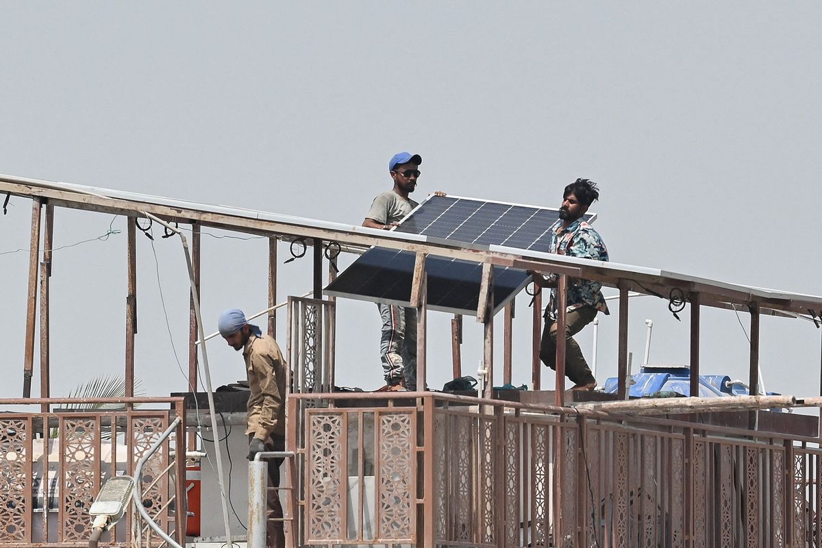 Technicians install solar panel plates on the rooftop of a house on a hot summer day in Karachi on May 27, 2024. (ASIF HASSAN/AFP via Getty Images)