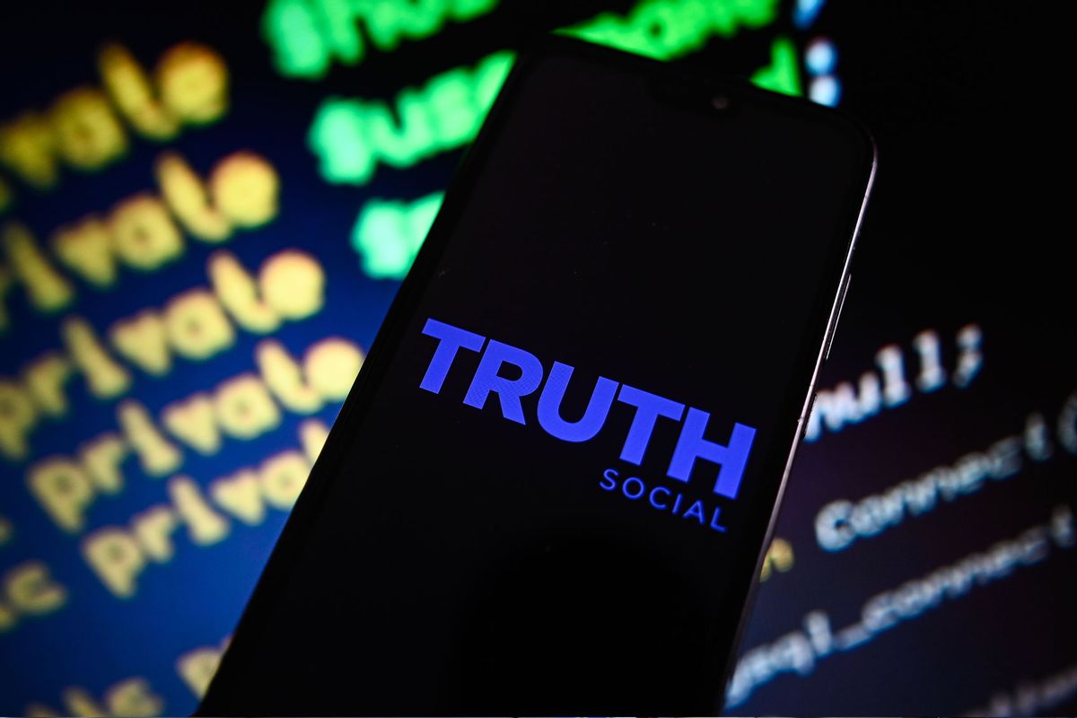 A Truth Social logo is displayed on a smartphone with coding lines in the background. (Omar Marques/SOPA Images/LightRocket via Getty Images)