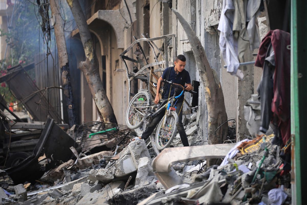 A Palestinian boy carries his bicycle as he climbs over debris a day after an operation by the Israeli Special Forces in the Nuseirat camp, in the central Gaza Strip on June 9, 2024. (EYAD BABA/AFP via Getty Images)