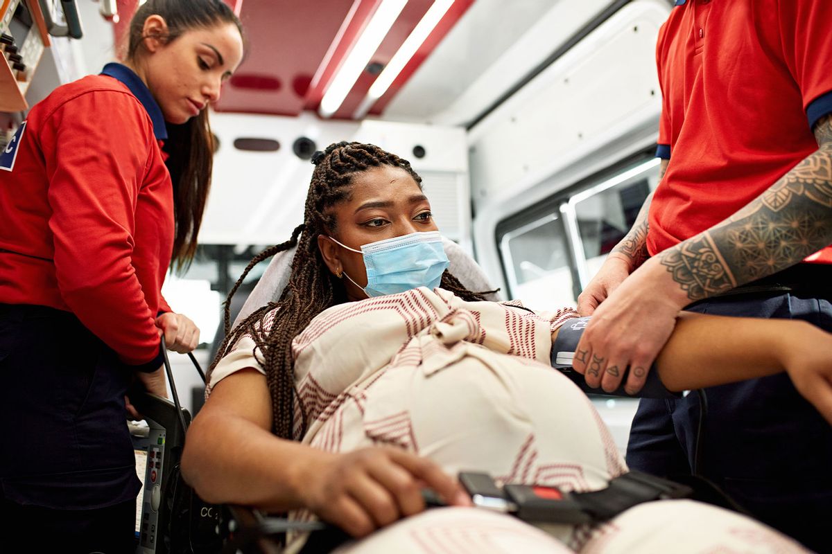 Pregnant woman being cared for inside ambulance (Getty Images/xavierarnau)