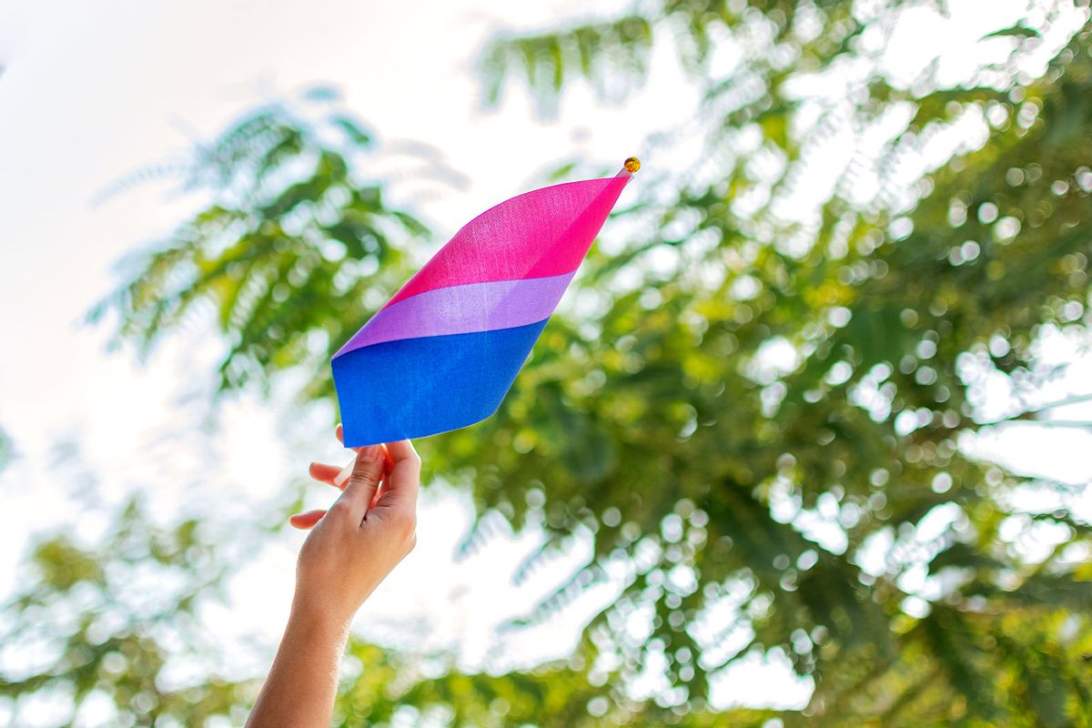 Woman holding a bisexual pride flag (Getty Images/Wirestock)