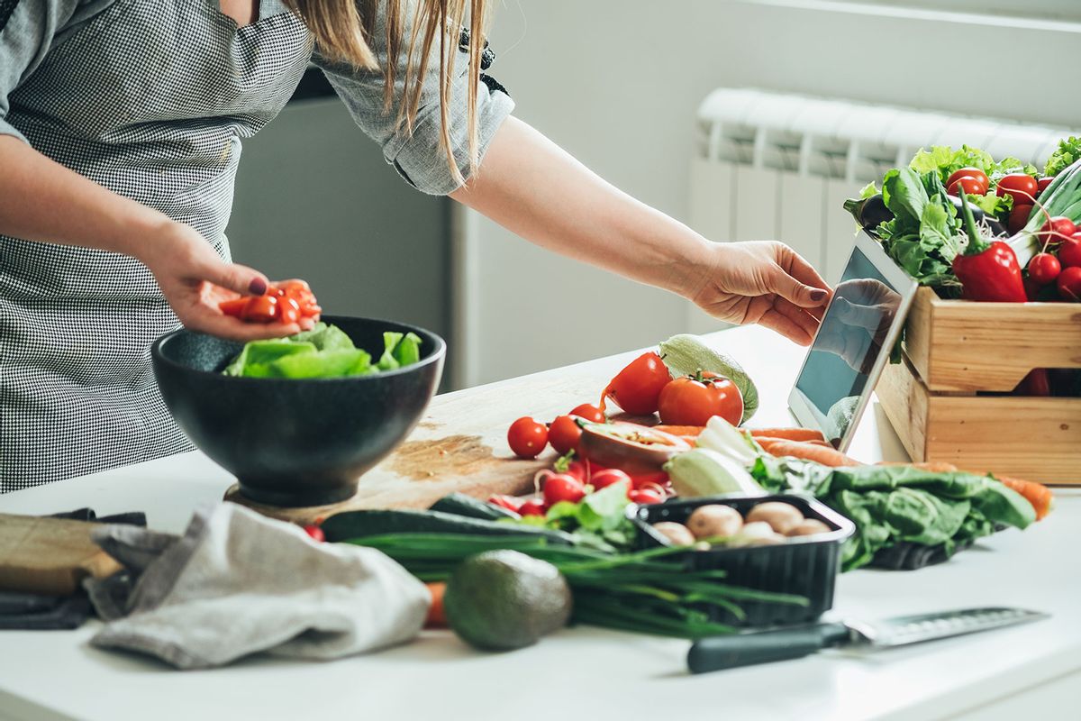 Woman utilizing tablet in the kitchen while cooking (Getty Images/Tijana Simic)