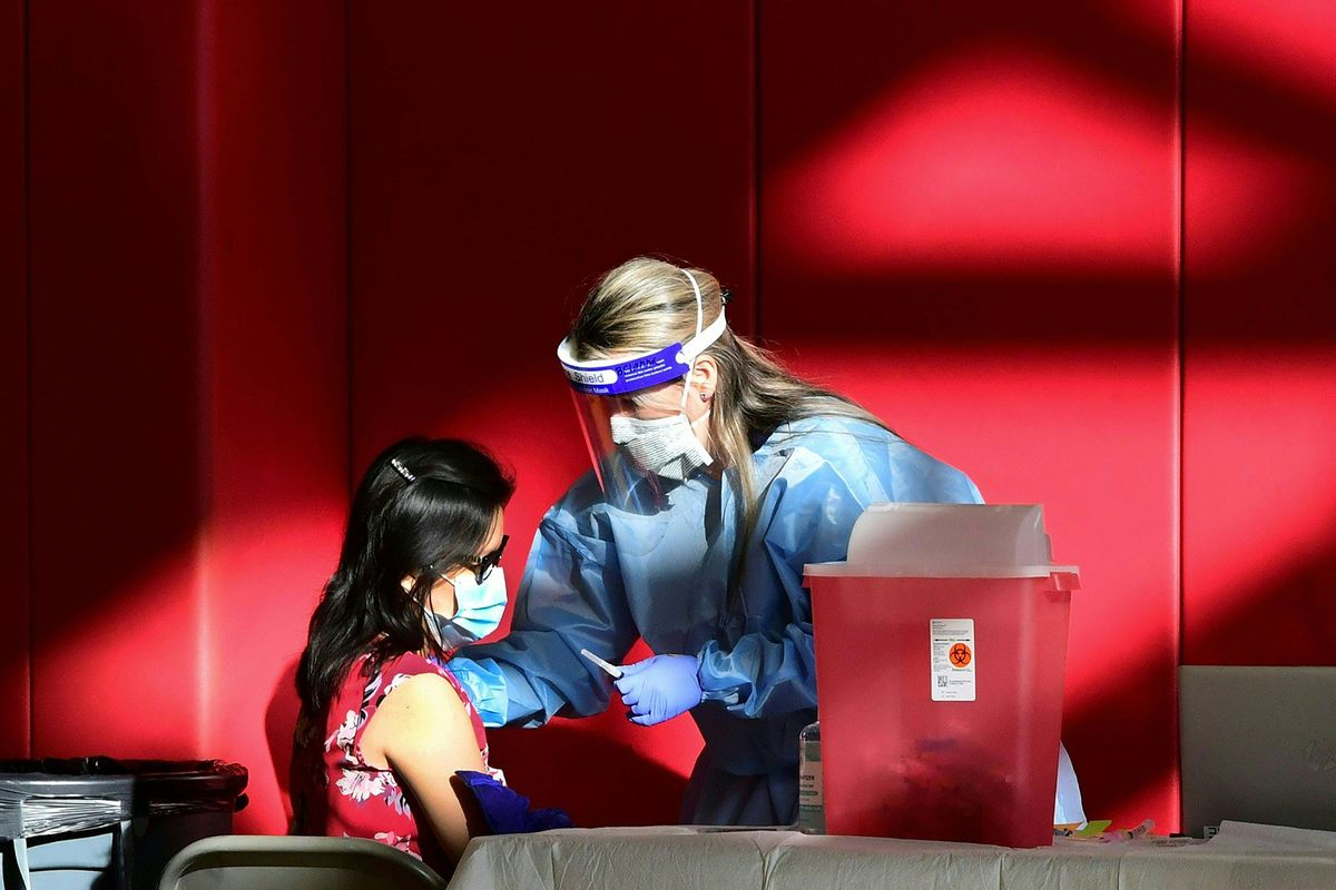 A registered nurse administers the COVID-19 vaccine into the arm of a woman at the Corona High School gymnasium in the Riverside County city of Corona, California on January 15, 2021. (FREDERIC J. BROWN/AFP via Getty Images)