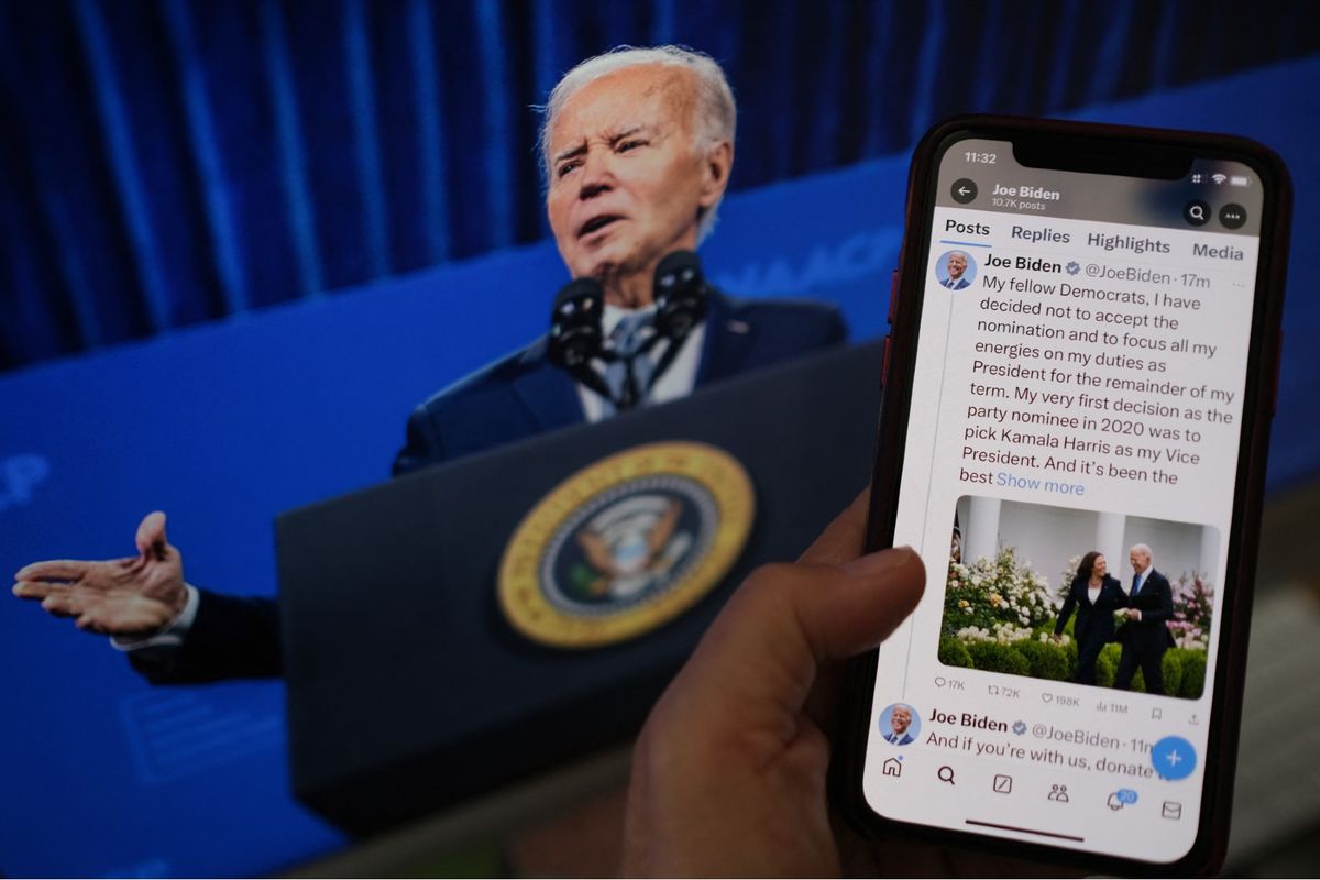 In this illustration photo taken in Los Angeles on July 21, 2024, a person reads the X account of U.S. President Joe Biden announcing he is not accepting the Democratic nomination for the 2024 presidential elections in front of a screen with his photo. (CHRIS DELMAS/AFP via Getty Images)