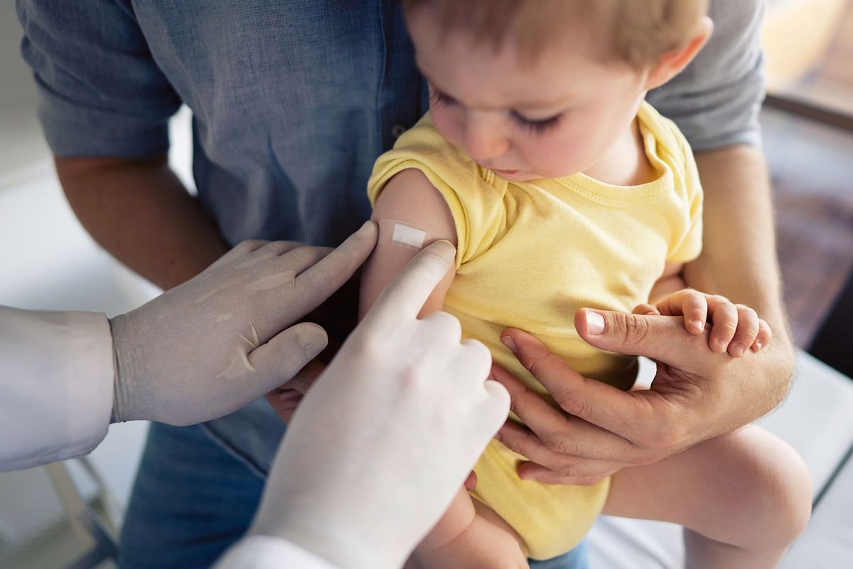 Doctor putting a patch on the little boy's shoulder after successful vaccination. (Getty Images/SrdjanPav)