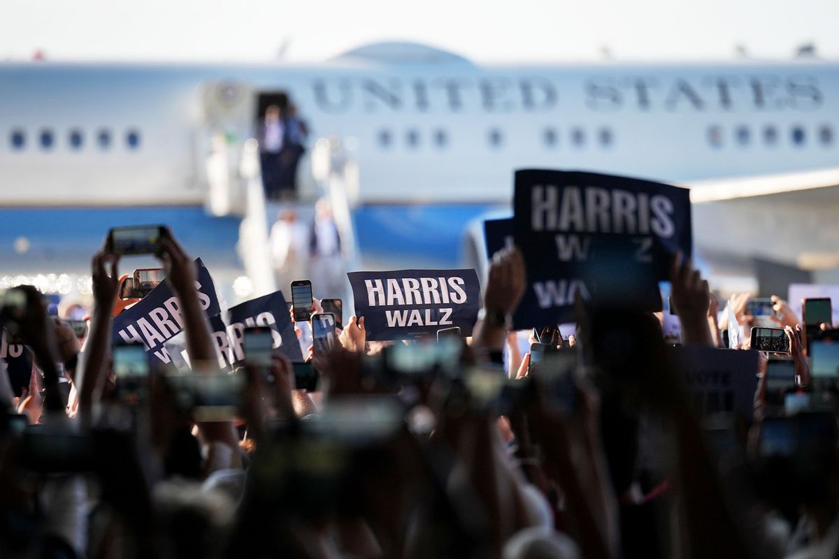 People hold campaign signs as Democratic presidential candidate, U.S. Vice President Kamala Harris and Democratic vice presidential candidate Minnesota Gov. Tim Walz walk off a plane together for a campaign event on August 7, 2024 in Detroit, Michigan. (Andrew Harnik/Getty Images)