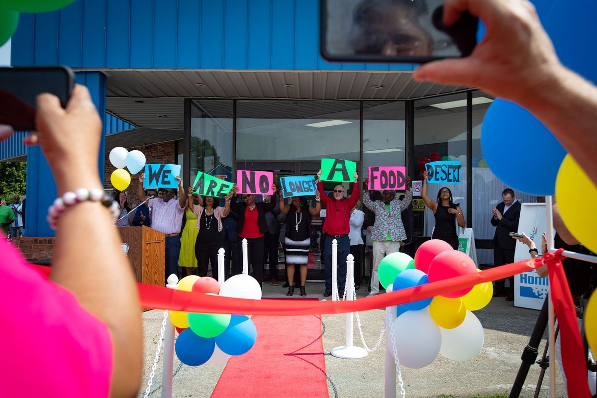 Board members and other stakeholders raise signs reading, “We are no longer a food desert,” at the grand opening of Rise Community Market in Cairo, Illinois, in June 2023. (Photo by Julia Rendleman)