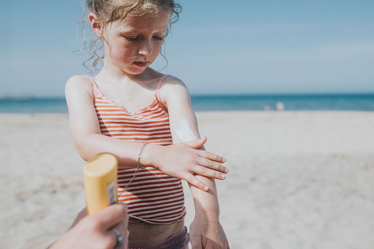 Child applying sunscreen on a beach (Getty Images/Catherine Falls Commercial)