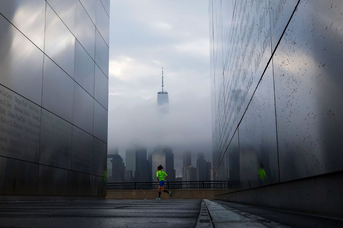 Fog shrouds the skyline of lower Manhattan and One World Trade Center as the sun rises in New York City as a person runs past the Empty Sky 9/11 Memorial on September 11, 2023, in Jersey City, New Jersey. (Gary Hershorn/Getty Images)