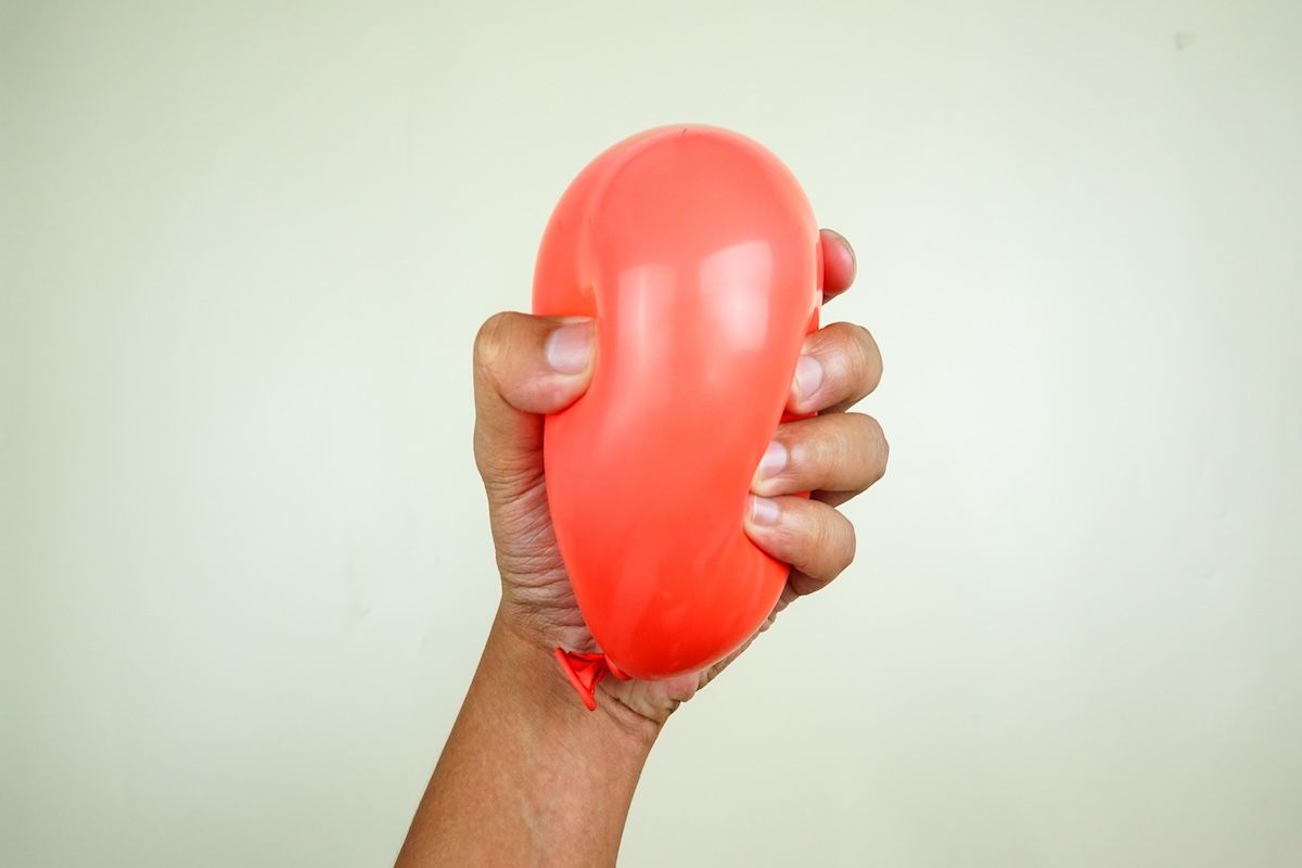 Squeezing a red balloon. (Nugroho Ridho, Moment / Getty Images )