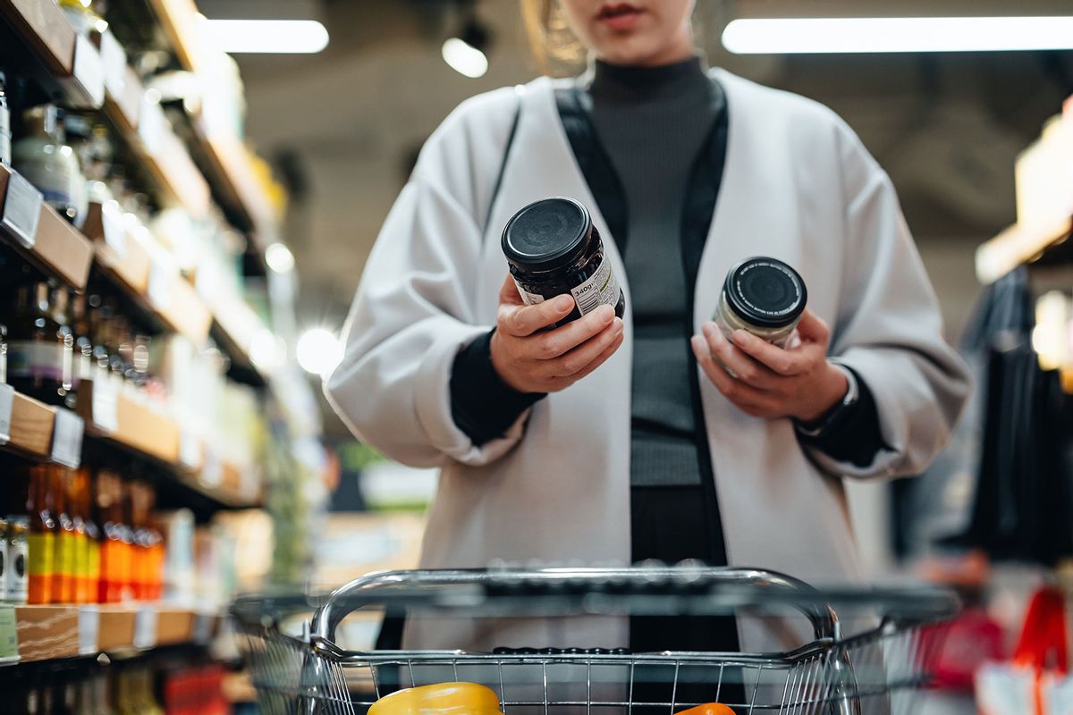 Woma in supermarket reading and comparing the product information of two bottles of cooking sauces. (Getty Images/d3sign)